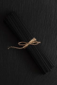 Sheaf of black spaghetti on black background Stock Photos