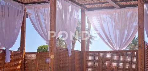 Sheds awning with fabric white curtains on the seashore breeze in the wind Stock Photos