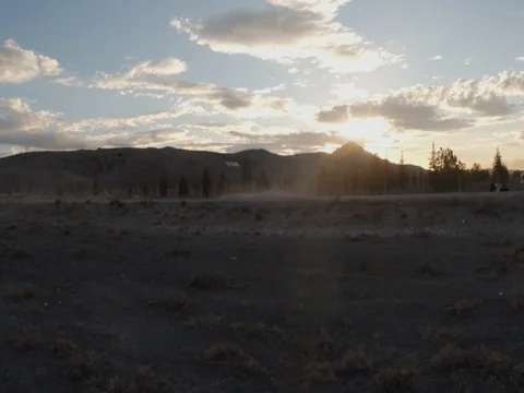 Sheep follow the shepherd in the setting sun in the dust on background mountains Stock Footage 77879738