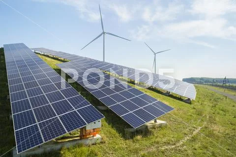 Sheep grazing near solar panels and wind turbine built on a former waste dump. Stock Photos