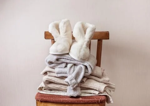 Sheepskin slippers, stack of warm clothes Stock Photos