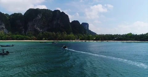 Sheer cliff wall rising above a busy white sand bay Stock-Footage 71297050
