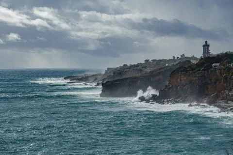 Sheer coastline with lighthouse Stock Photos
