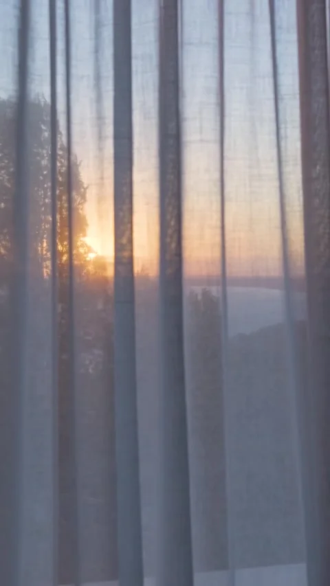 Sheer curtain gently moving in front of sunrise Stock Footage 294963958