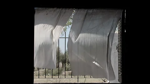 Sheer Curtains Blowing in the Wind Through an Open Window with Iron Grille - 4K Stock Footage 339606679