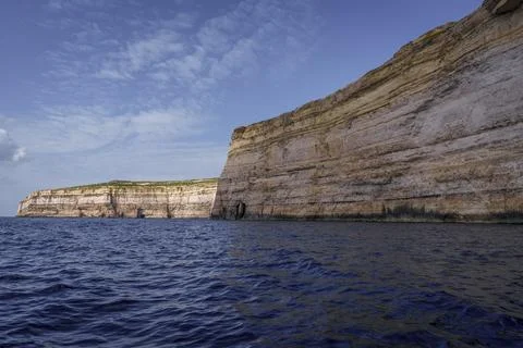 Sheer Limestone Sea Cliffs under Clear Evening Sky and Dark Waves Stock Photos