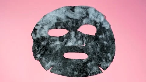 Sheet of black bubble mask on pink background close-up, timelapse. Stock Footage 194520565
