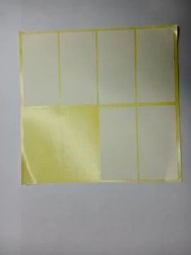 Sheet of blank white adhesive label stickers with two labels missing. Stockfoto's