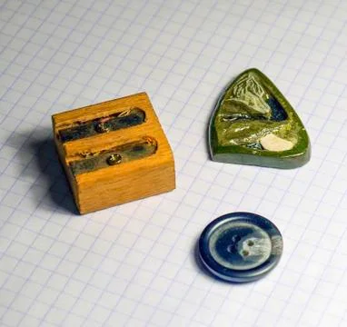 On a sheet of notebook pencil sharpener, a button and a stone am Stock Photos