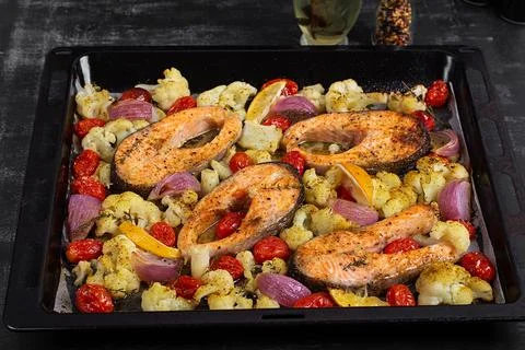 Sheet Pan Salmon and Vegetables on Dark Background. Overhead Stock Photos