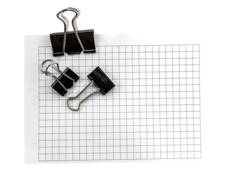 A sheet of paper in a cage for notes with a paper clip on a white backgroun.. Stock Photos