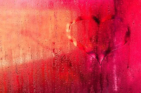 Sheet of transparent window covered in moisture. red wet glass background. .. Stock Photos