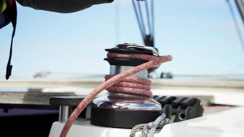 Sheet winch close-up. Sailor wearing gloves pulls the handle of a winch. Stock Footage 240395227