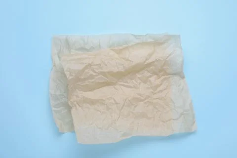 Sheets of crumpled baking paper on light blue background, top view Stock Photos