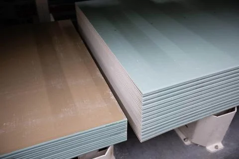 Sheets of moisture-resistant drywall of different brands are stacked in bundles Stock Photos