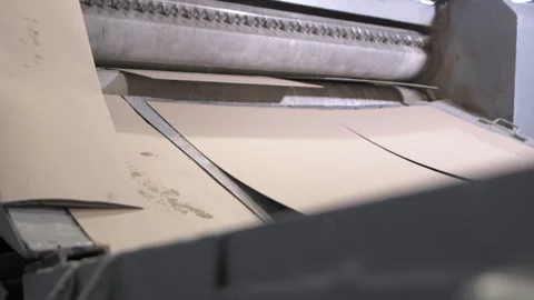 Sheets pass through rollers of machine to level surface in shop Stockbeeldmateriaal 294201373