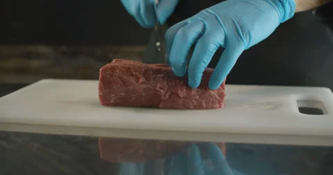 Сhef cuts raw meat with the knife in Slow Motion. Video 4K Stock Footage 103540159
