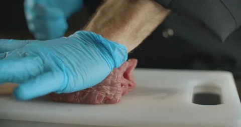 Сhef in gloves beats off piece of beef with palm. Video in slow motion in 4K Stock Footage 103539401