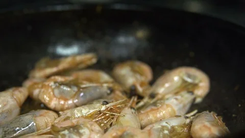 Сhef in the kitchen prepares shrimp on a hot pan sprinkling them with spices Vídeo Stock 103310559