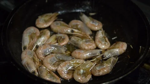 Сhef in the kitchen prepares shrimp on a hot pan sprinkling them with spices Video stock 103310607