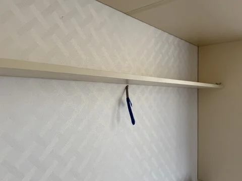 Shelf installation process with screwdriver on textured wall, room maintena.. 스톡 사진