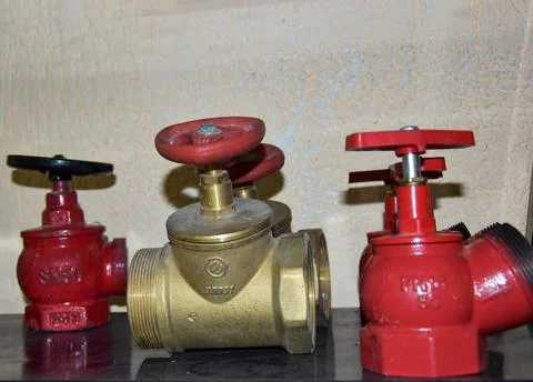 On the shelf there are three different brass straight-flow valves and cast-iron Stock Photos