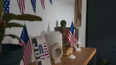 Shelf with Two US Flags, Fourth of July on Calendar, Triangle Bunting on Wall Stock Footage 310739430