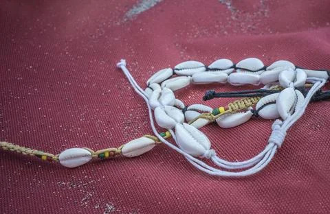 Shell ankle bracelet over red sailcloth fabric Stock Photos