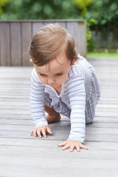 Shell be walking soon. a cute little baby crawling around on a patio deck. Stock Photos