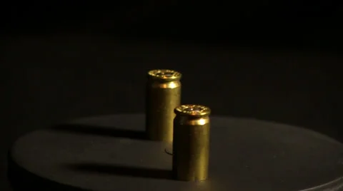 Shell casings rotating against black background Видео 32659783