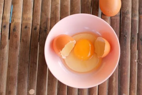 Shell with egg and open Eggs in a pink bowl on Bamboo battens. Top view close Stock Photos