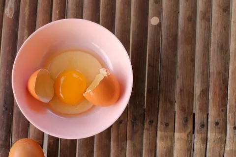 Shell with egg and open Eggs in a pink bowl on Bamboo battens. Top view close Stock Photos