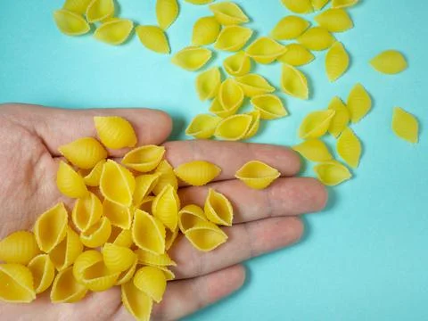 Shell-shaped pasta falls from your hand. Italian food. Cuisine of the peoples Stock Photos
