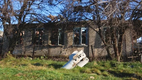 A shell sticks out of the ground against the background of a destroyed house Stock Footage 224841722