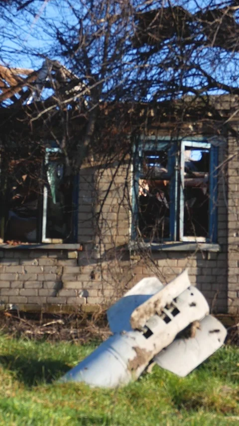 A shell sticks out of the ground against the background of a destroyed house Stock Footage 311976010