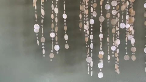 Shell wind chimes swaying gently in the breeze against green wall background. Stock Footage 345101912