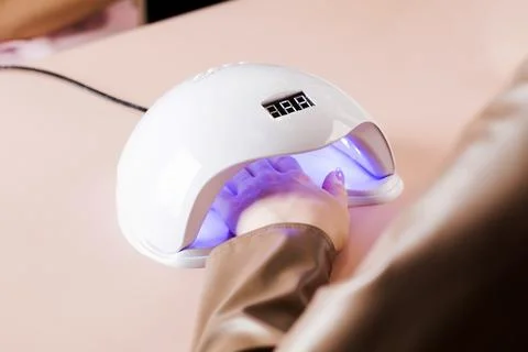 Shellac coated manicure. Drying process of gel polish in an ultraviolet lamp. Stock Photos