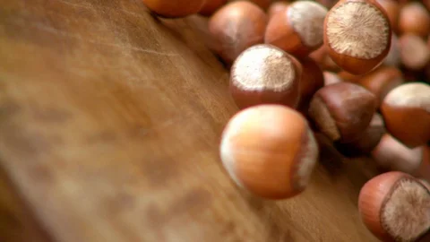 Shelled hazelnuts on wooden surface move in to camera in slow motion. Macro Stock Footage 128977482