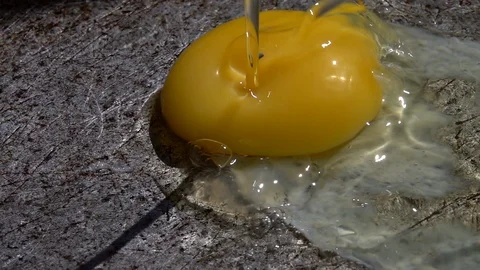 Shelled raw egg, falling on old scratched frying metal plate with sizzling oil Stock Footage 96885797
