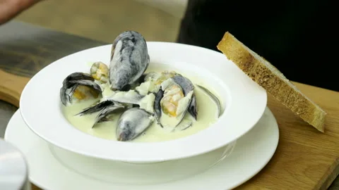 Shellfish seafood. Close-up of cooked mussels in cream sauce on white plate. 4K Stock-Footage 91748806