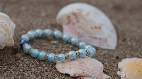 Shells and bracelet on the sand at the beach Stock Footage 344889706