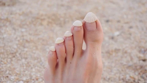 Shells on female toes. Point of view of feet in the sand. 動画素材 115951051