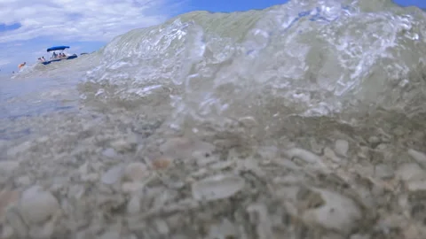 Shells washed ashore as waves crash over the camera Stock Footage 147980711