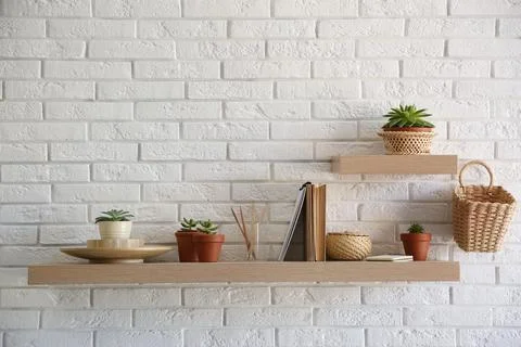 Shelves with decorative elements on white brick wall. Interior design Stock Photos