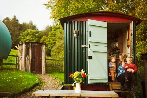 A shepherd's hut with open door beside a path to a small rustic shed, and a Stock Photos