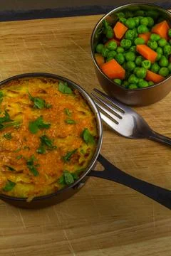 Shepherds or cottage pie in serving dish with parsley on wooden board, portra Stock Photos