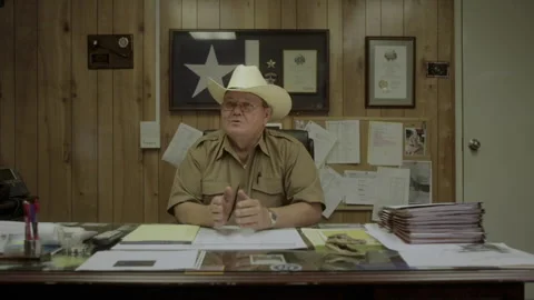 A sheriff talks about local problems while sitting at his desk in his office Stock Footage 327957248