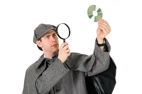 Sherlock: man examines cd with magnifying glass Stock Photos