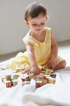 Shes a bright little girl. a cute baby girl sitting on the floor playing with Stock Photos