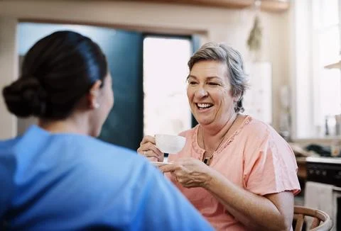 Shes got plenty of stories to share. a young female caregiver chatting to a Stock Photos